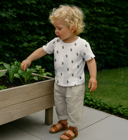 93496-Rippjersey-Rib-Jersey-Stoff-Bio-Baumwolle-Blitze-natur-gruen-1-2m-Breite-Screenshot-2025-12-21-222941.png Kind trägt T-Shirt aus Rippjersey Bio Baumwolle mit grünen Blitzen auf naturfarbenem Grund