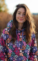 93498-Sweatstoff--Melange-Blumen-Blueten-abstrakt-natur-rosa-lila-1-38m-Breite-Screenshot-2025-12-22-194201.png Mädchen trägt Hoodie aus Sweatstoff mit buntem Blumenmuster