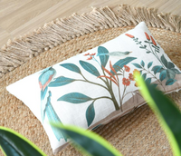 Dekokissen mit Vogel-, Blumen- und Blätterdessin in Naturtönen auf einem Naturteppich