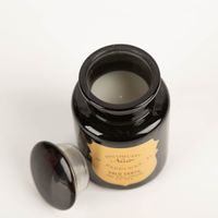 Die hochwertige Duftkerze Sojakerze Apothecary Noir Palo Santo 226gr von Paddywax besticht durch ihr elegantes, glänzend schwarzes Apothekerglas mit goldfarbenem Etikett. Ein luxuriöser Blickfang für Ihr Zuhause - Detailaufnahme