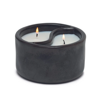 Die hochwertige Duftkerze Sojakerze Yin-Yang Black Palo Santo/Cade 311gr im Keramiktopf von Paddywax besticht durch ihr schwarzes Keramikgefäß in geschwungener Yin-Yang-Form. Ein dekoratives Highlight für moderne Akzente - flackernd in Szene gesetzt