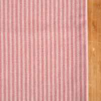 Detailaufnahme des Tischläufers aus Dobbystoff mit feinem rosa-ecru Streifenmuster und sauber vernähter Kante.