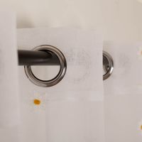 Transparenter weißer Ösenvorhang mit gelber Blütenstickerei in 140x260 cm. Er verleiht Räumen eine luftige Leichtigkeit und lässt sich dank der Metallösen schnell und einfach an jeder Gardinenstange dekorieren - Schlaufendetailaufnahme