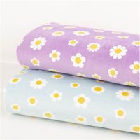 Weicher Nicki-Stoff in hellem Blau präsentiert ein harmonisches Muster aus weißen Gänseblümchen mit gelben Akzenten. Das Textil überzeugt durch seine samtige Haptik sowie eine großzügige Breite von 1,45 Metern für kreative Nähprojekte - in Szene gesetzt