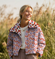 94460-Steppstoff-Musselin-Stoff-Blumen-Retro-natur-rot-lila-1-30m-Breite-Screenshot-2026-04-12-141605.png Frau im Freien trägt eine kurze Jacke aus gesteppter Musselin-Meterware mit Blumen-Retro-Muster in Natur, Rot und Lila