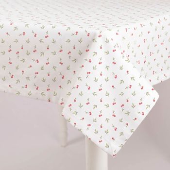 Weiße Tischdecke mit kleinen roten Kirschen und grünen Blättern, dekorativ über einen Tisch drapiert