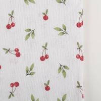 94677-Tischdecke-Kirschen-weiss-rot-gruen-145x200cm-IMG-5197.jpg Nahaufnahme der Tischdecke mit feinem Kirschmotiv und sichtbar strukturierter Baumwolloberfläche