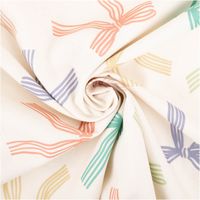 Baumwollpopeline mit locker gestreuten Schleifen in Mint, Grün, Lila, Rosa und Apricot auf wollweißem Grund – luftig, verspielt und feminin. Breite: 1,45 m. Ideal für Kleider und Nähprojekte - kunstvoll eingedreht in Falten