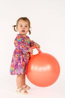 Kind im Kleid aus Giraffenstoff mit großem Hüpfball in einem Fotostudio