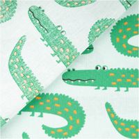 Nahaufnahme von Stoff mit grünem Krokodilmuster auf hellem Hintergrund, Detail des Designs.