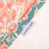 Vorhang Baumwolle Blumenornamente rosa petrol mit Smok-Schlaufenband Farbenfrohes Blumenmuster auf Stoff, Nahaufnahme mit Label von SCHOENER LEBEN sichtbar.