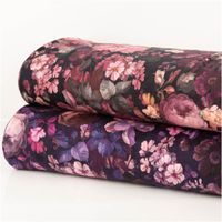 Sweatstoff aus Baumwolle Blüten Digitaldruck marine 1,48m Breite Floral gemusterter Stoff in Rosa und Lila, zwei aufgerollte Bahnen mit dunklem Hintergrund.