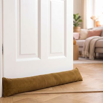 SCHÖNER LEBEN. Zugluftstopper Cord Baumwolle grob oliv-grün verschiedene Größen von SCHÖNER LEBEN. Zugluftstopper aus grobem oliv-grünem Cord liegt quer vor einer weißen Tür auf Parkettboden