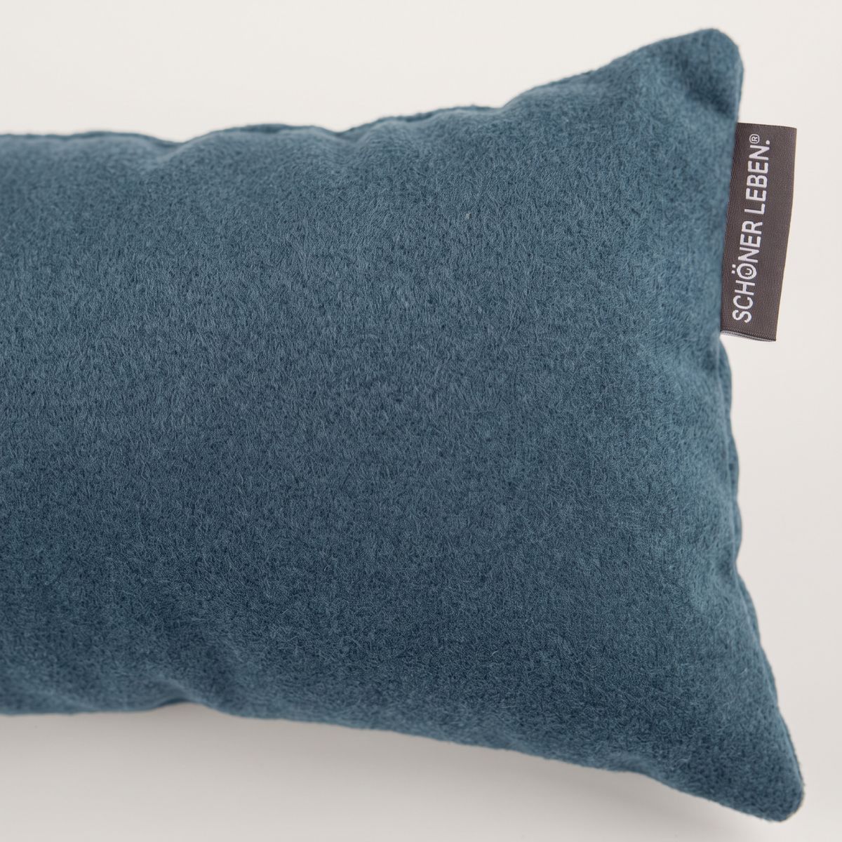 Nahaufnahme eines blauen Fleece-Zugluftstoppers mit sichtbarem SCHÖNER LEBEN Etikett