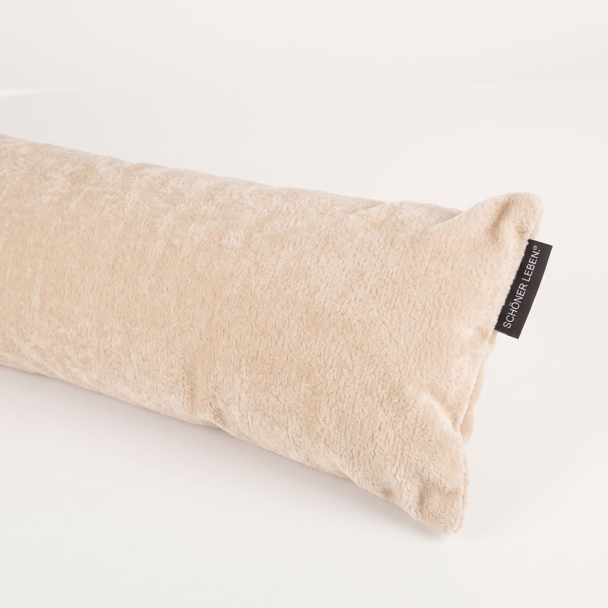 seitlich liegender cremefarbener Zugluftstopper aus Teddy Stoff, sichtbares SCHÖNER LEBEN. Textiletikett