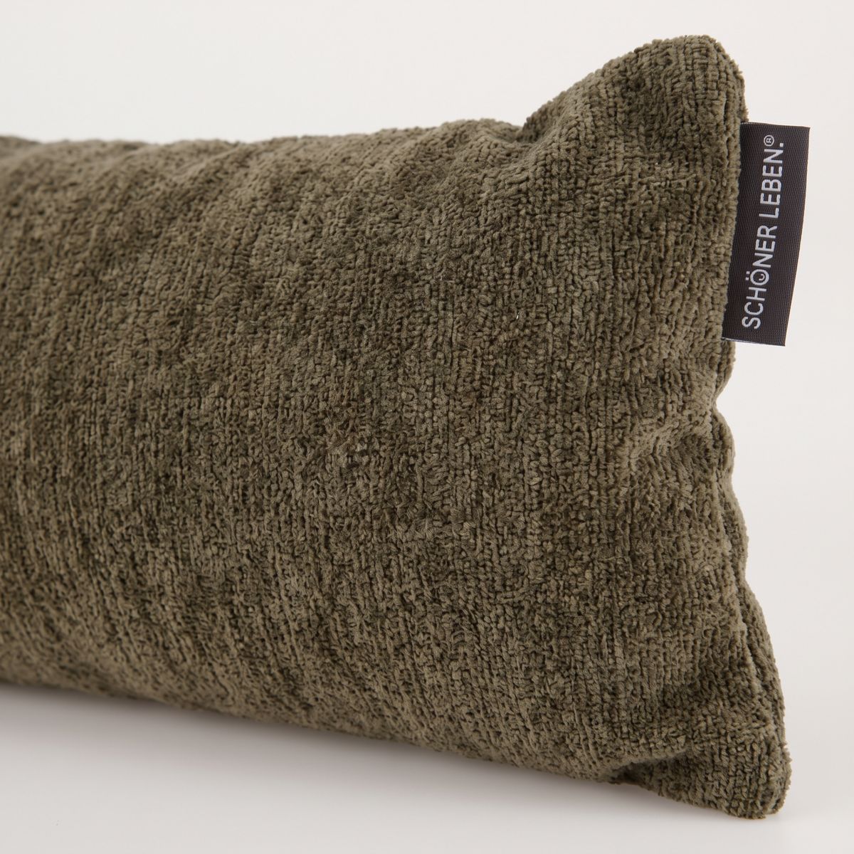Detailaufnahme von moosgrünem Zugluftstopper aus Soft-Teddy-Stoff mit sichtbarem Stoffetikett