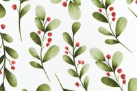 Abwaschbarer Tischdeckenstoff mit grünen Zweigen und roten Beeren auf Weiß, Detailaufnahme der Oberfläche.
