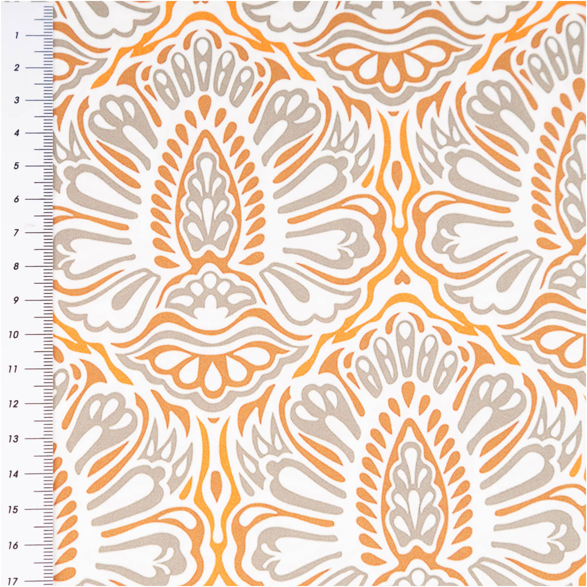 Nahaufnahme des orientalischen Musters in Orange und Beige auf Stoff mit Meterstab links.