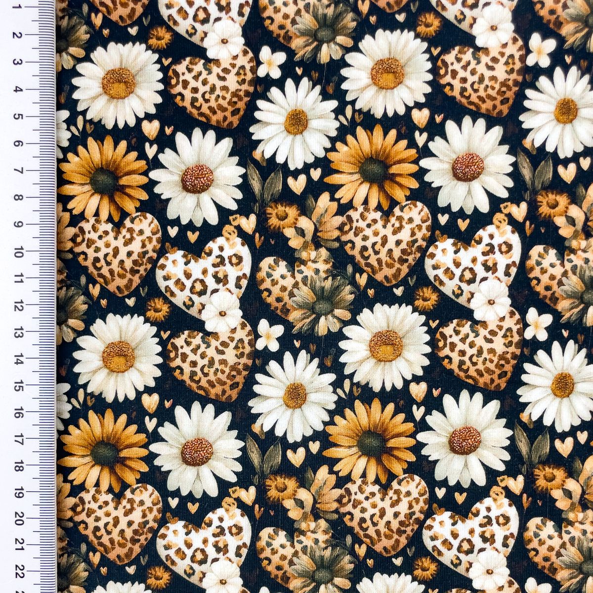95851-Jersey-Stoff-Baumwolljersey-Digitaldruck-Daisy-Leo-Herzen-Blumen-schwarz-weiss-senfgelb-1-5m-Breite-S2650R-3684-1.jpg Baumwolljersey mit Gänseblümchen, Herzen und Leomuster auf schwarzem Grund, flach liegend mit Maßband