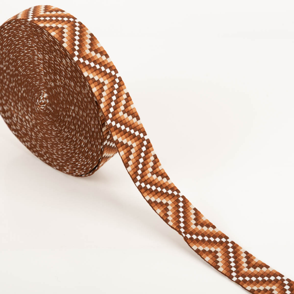 Gurtband Zickzack Chevron braun orange weiß 3,8cm Breite Braunes Gurtband mit Zickzackmuster in orange und weiß als Rolle auf hellem Hintergrund