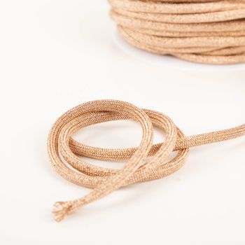 Kordel Kettengeflecht flach Metallic altrosa 8mm Breite metallic altrosa Kordel aus Kettengeflecht locker zur Spirale gelegt, Garnrolle im Hintergrund