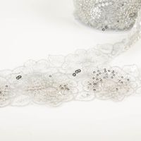 Borte bestickt Blumen Perlen Pailletten weiß silber 7,5cm Breite Borte mit silbernen Blumen, bestickt mit Perlen und Pailletten, seitlich abgerollt auf weißem Untergrund