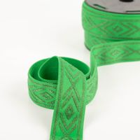 stoffliches elastisches Band in Grün mit silbernen Rauten, ausgerollt und mit Teil der Rolle im Hintergrund