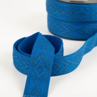 Gummiband Glitzer Rauten geometrisch königsblau silber 4cm Breite königsblaues Elastikband mit silbernem Rautenmuster in schwungvoller Form, Hintergrund zeigt Band auf Rolle