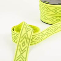Gummiband Glitzer Rauten geometrisch neongelb silber 4cm Breite glänzendes gelbes Gummiband mit Rautenmuster in Nahaufnahme, vorn locker gewickelt, dahinter auf einer Rolle