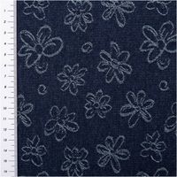 Blauer Jacquardstoff mit weißen Blumenmustern und Maßband links, strukturierte Nahansicht des Materials