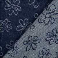 Jeans Jacquardstoff in Dunkelblau mit weißen Blumenmotiven, Kante aufgeschlagen, Vorder- und Rückseite sichtbar