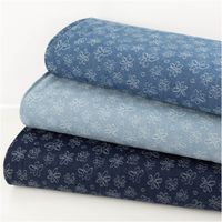 Drei Lagen Jacquard Jeansstoff in unterschiedlichen Blautönen mit weißen Blumenmustern als Stoffstapel