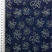 Jeansstoff in Dunkelblau mit eingewebten weißen Jacquard-Blumen, flach liegend mit Maßband am Rand