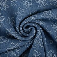 Jacquard Denimstoff jeansblau mit weißen Blumen, zur Spirale gedreht und Muster im Stoff sichtbar