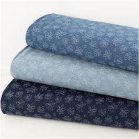 drei Rollen Jeansstoff mit weißen Jacquard-Blumen in verschiedenen Blautönen gestapelt