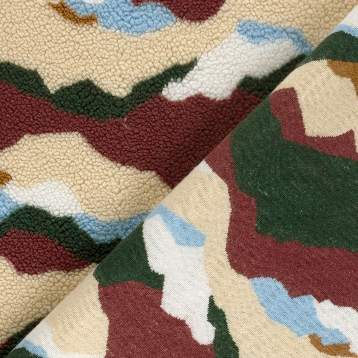Umgeschlagene Ecke zeigt die glatte Rückseite des Sherpa Fleece mit abstrakten W Umgeschlagene Ecke zeigt die glatte Rückseite des Sherpa Fleece mit abstrakten Wellen in Grün, Hellblau und Creme