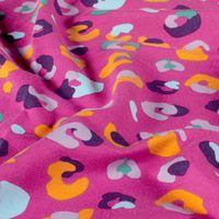 French Terry Stoff mit buntem Leomuster in Orange, Flieder und Hellblau auf Pink, weich drapiert