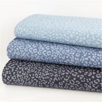 Jeansstoff Leo Leomuster bedruckt jeansblau hellgrau 1,5m Breite drei Stoffstapel mit unterschiedlich dunklem jeansblauem Grund und hellgrauem Leomuster übereinander gelegt