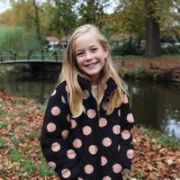 Mädchen in einer marineblauen Teddyjacke mit rosa Punkten in einem herbstlichen Park am Teich Mädchen in einer marineblauen Teddyjacke mit rosa Punkten in einem herbstlichen Park am Teich