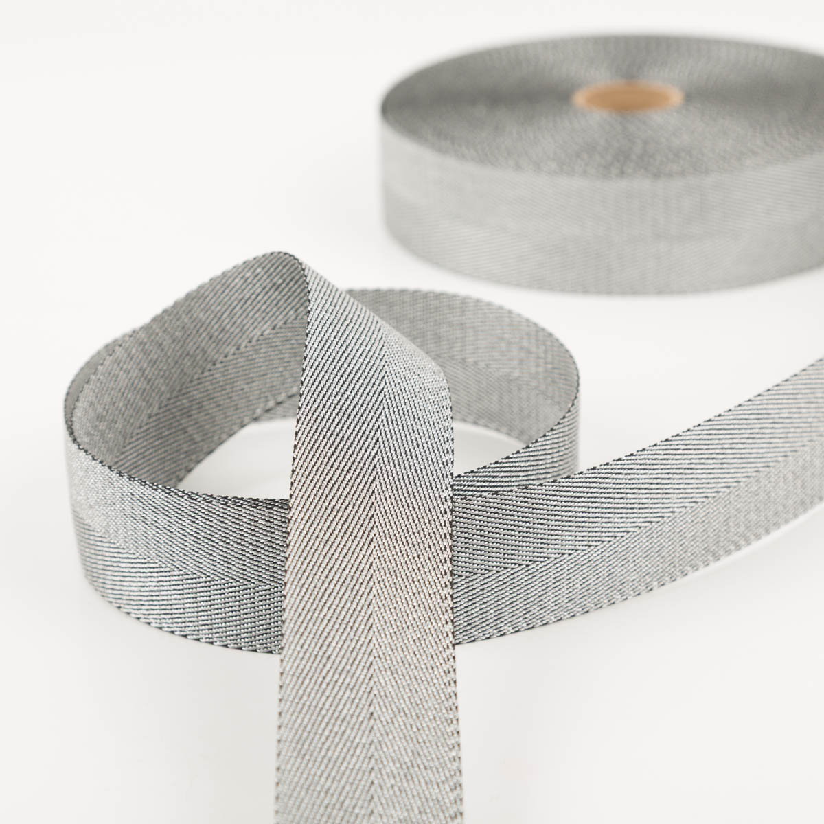 Gurtband metallic Lurex silber schwarz 4cm zur Schlaufe gelegt vor der Rolle, schimmernde Oberfläche