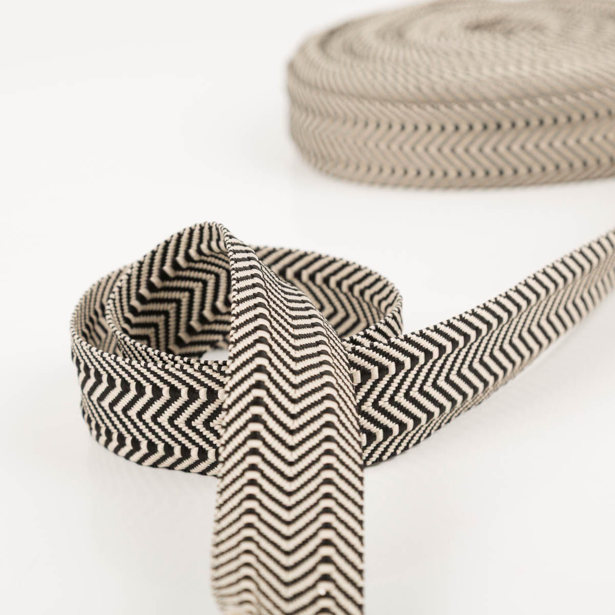 96581-Gurtband-doppeltes-Zickzack-schwarz-3-8cm-Breite-IMG-0229.jpg Gurtband doppeltes Zickzack schwarz 3,8cm zur Schlaufe gelegt vor der Rolle, Vorder- und Rückseite sichtbar