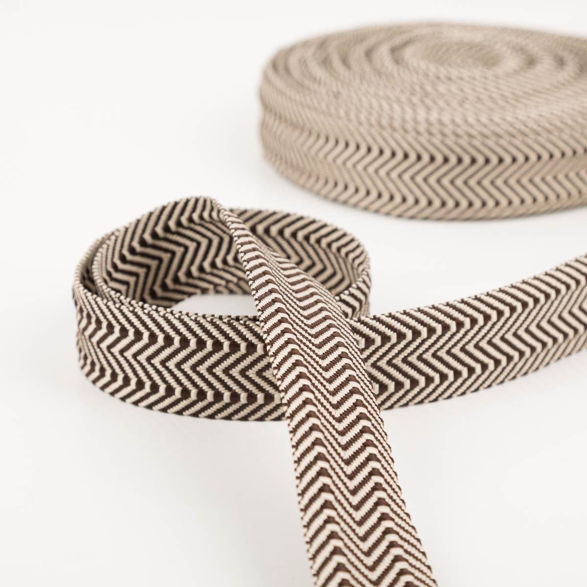 96587-Gurtband-doppeltes-Zickzack-kaffeebraun-3-8cm-Breite-IMG-0219.jpg Gurtband doppeltes Zickzack kaffeebraun 3,8cm zur Schlaufe gelegt vor der Rolle, Vorder- und Rückseite sichtbar