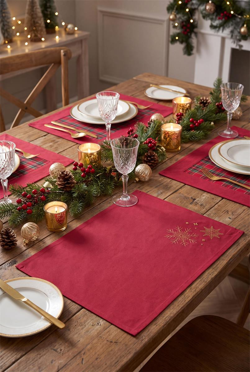 Rote Platzsets mit Tartan auf gedecktem Weihnachtstisch mit Kerzen