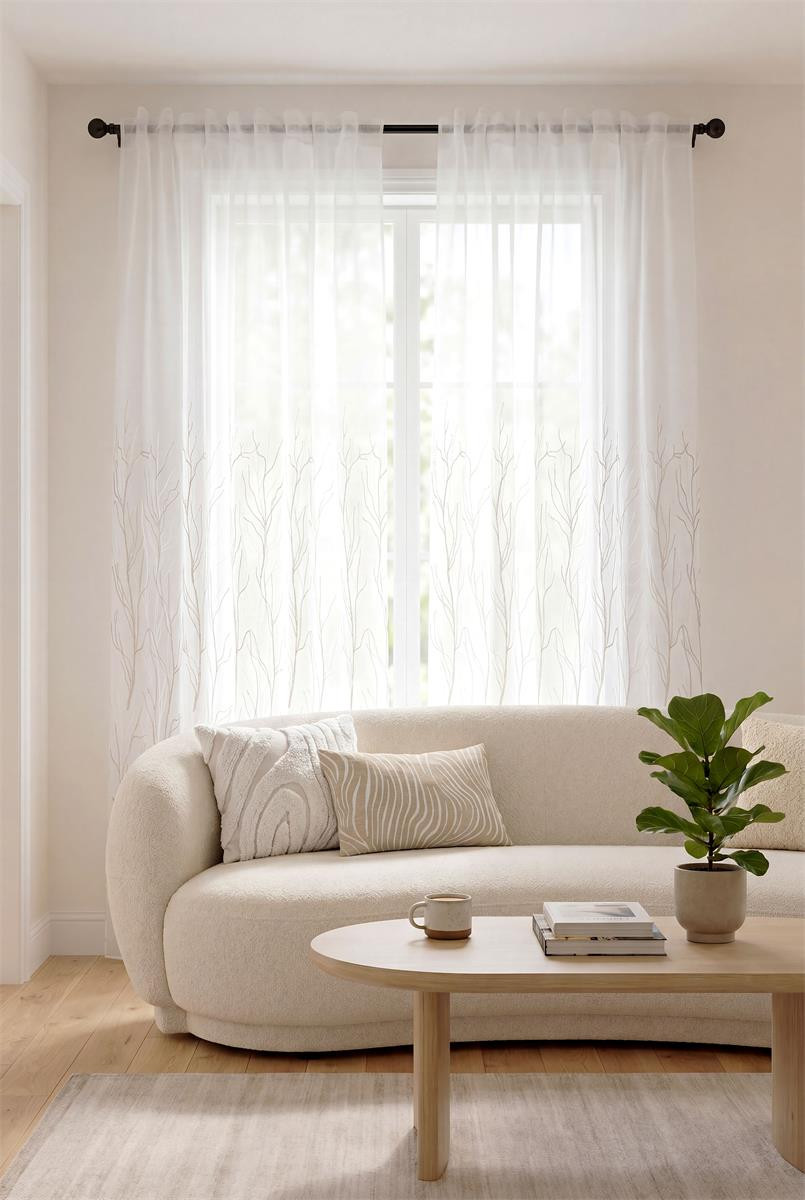 Weißer Voile-Vorhang mit Gräsern am Fenster eines hellen Wohnzimmers Weißer Voile-Vorhang mit Gräsern am Fenster eines hellen Wohnzimmers