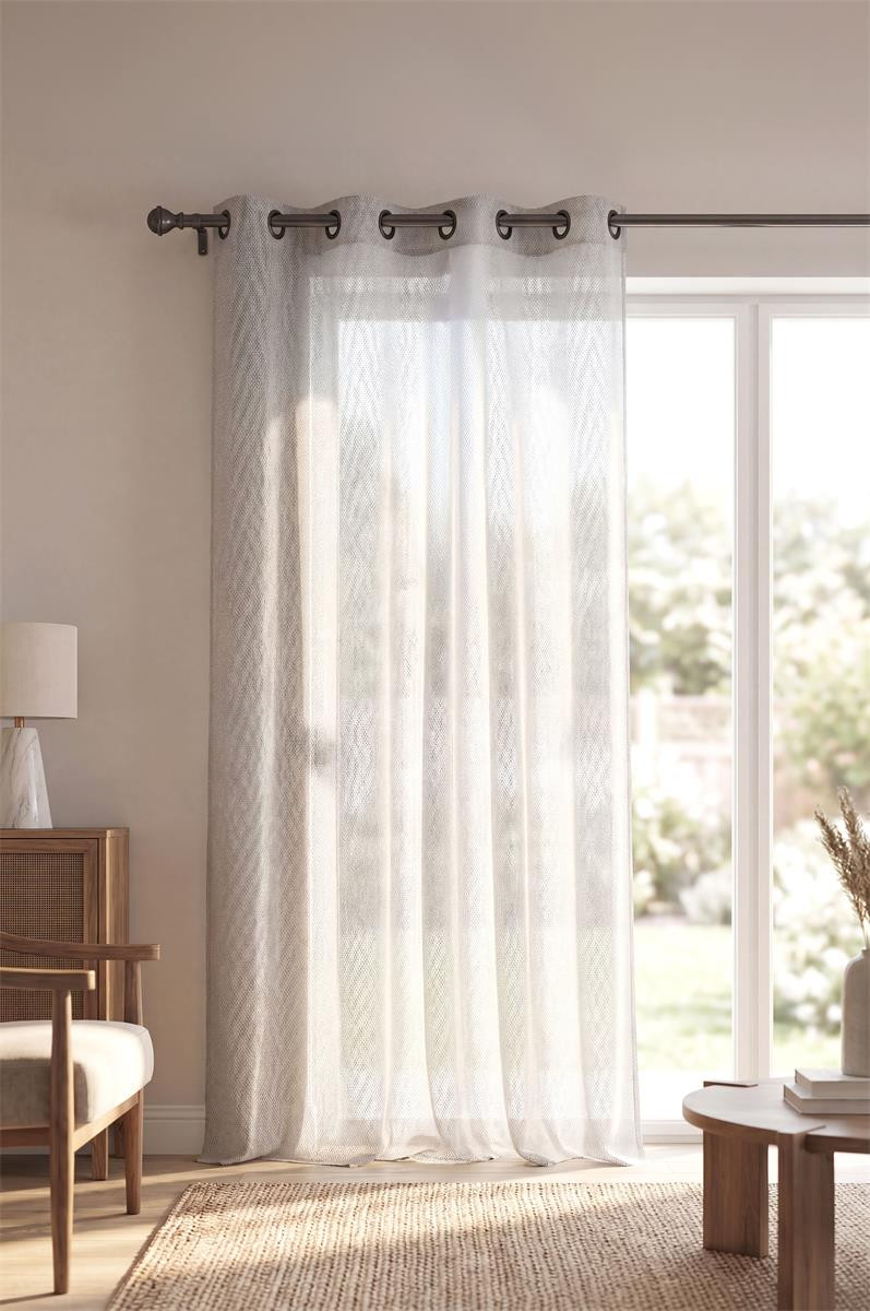 Ösenvorhang aus naturfarbenem Voile am Fenster eines hellen Wohnraums